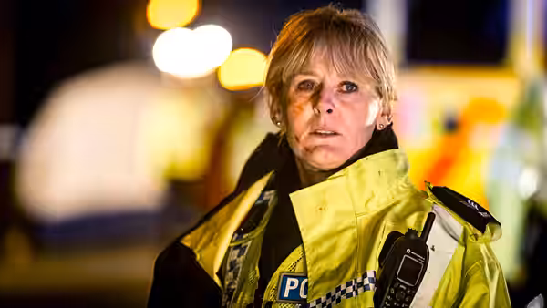 Catherine Cawood (Sarah Lancashire) stands at night in a high-visibility jacket