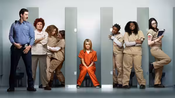 Piper Chapman (Taylor Schilling) sits in orange while inmates gather around bathroom stalls