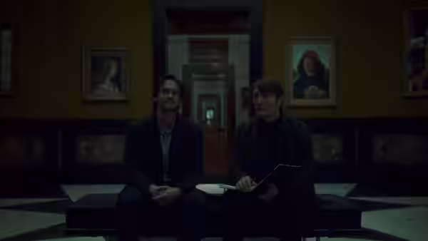 Two men seated on a bench in an ornate hallway