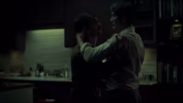 Two men grappling violently in a dark kitchen