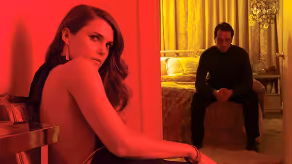 Elizabeth Jennings (Keri Russell) glancing back in red light as Philip Jennings (Matthew Rhys) sits on the bed