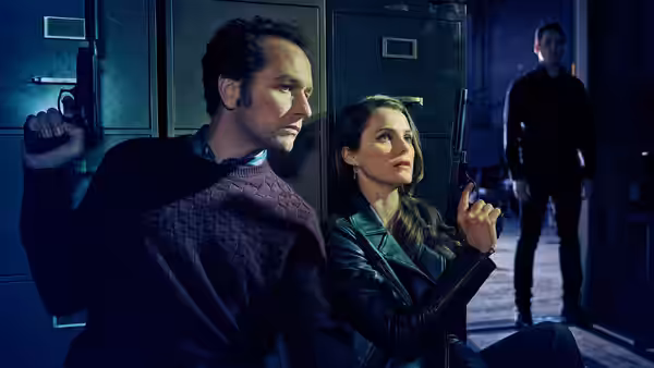 Philip Jennings (Matthew Rhys) and Elizabeth Jennings (Keri Russell) holding guns near metal lockers
