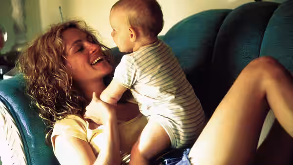 Erin Brockovich (Julia Roberts) smiling while holding a baby on a couch