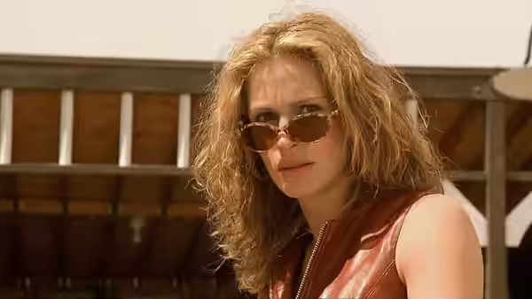 Erin Brockovich (Julia Roberts) wearing sunglasses outdoors by a wooden building