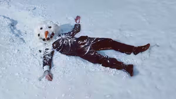 a person in a snowman costume lying on their back in the snow