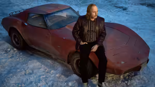 a man sitting on the hood of a red car in the snow