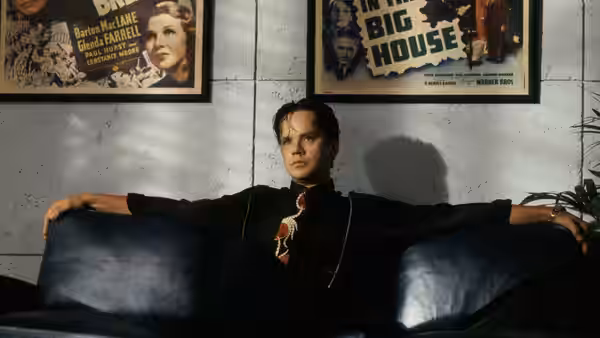 Griffin Mill (Tim Robbins) reclining on a blue couch beneath movie posters