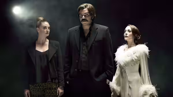 Steven Toast (Matt Berry) standing between two women under a spotlight