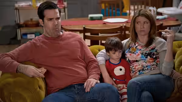 Rob (Rob Delaney) and Sharon (Sharon Horgan) with a boy on a yellow couch
