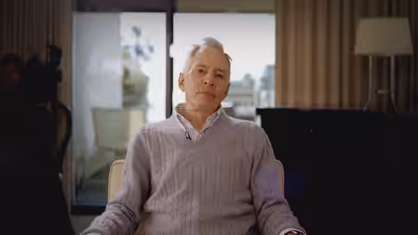 Robert Durst seated in a chair inside a living room
