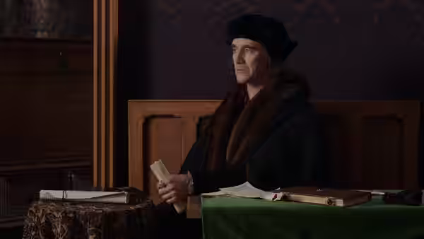 Cardinal Wolsey (Jonathan Pryce) sits at a table holding a letter
