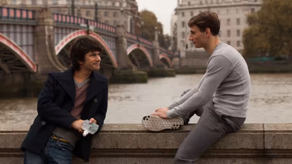 Danny (Ben Whishaw) and Alex (Edward Holcroft) talking on a riverside bridge