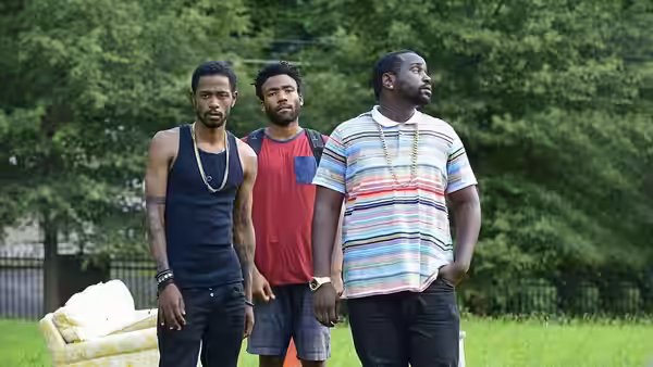 Three men standing side by side on a grassy lawn outdoors