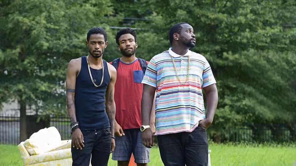 Three men standing side by side on a grassy lawn outdoors