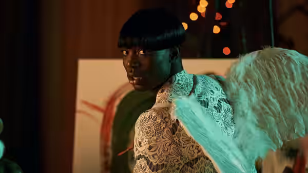 Man with bowl haircut and large feathered wings turning to look back