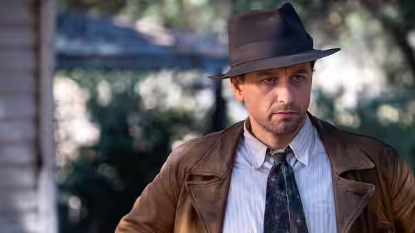 Perry Mason (Matthew Rhys) wearing a leather jacket and hat outdoors