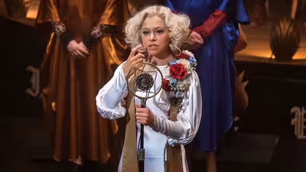 Sister Alice (Tatiana Maslany) holding a decorative mask on a stage