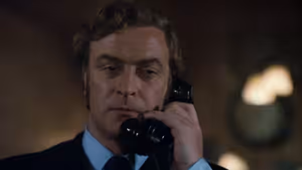 Jack Carter (Michael Caine) listening on a black telephone receiver