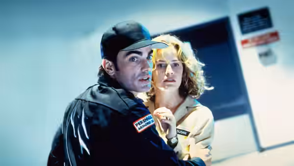 Tommy Dundee (William Fichtner) holds a woman close in a hallway
