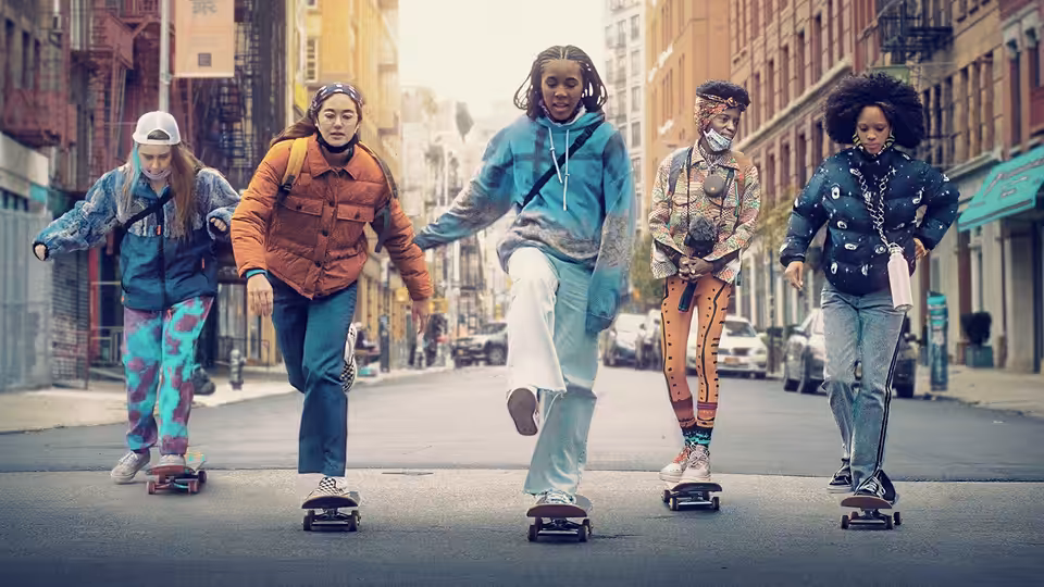 Five young women on skateboards linked together on a city street