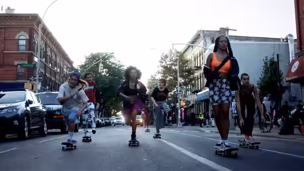 Group of skateboarders riding through a city intersection at dusk