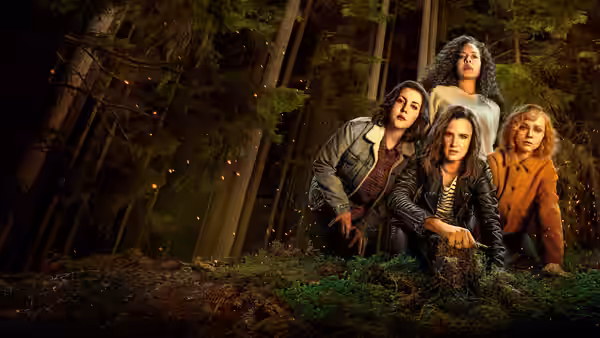 Four women stand together in a forest at night with lights around them
