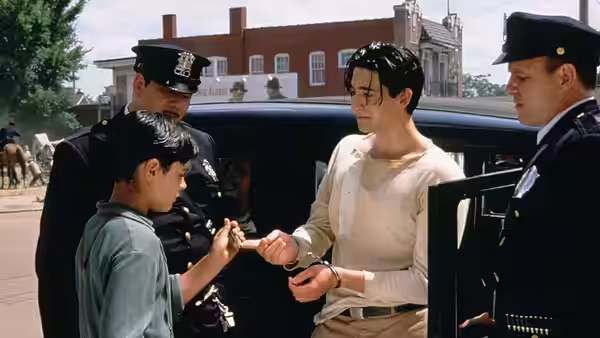 Two police officers stand with two boys beside a black car