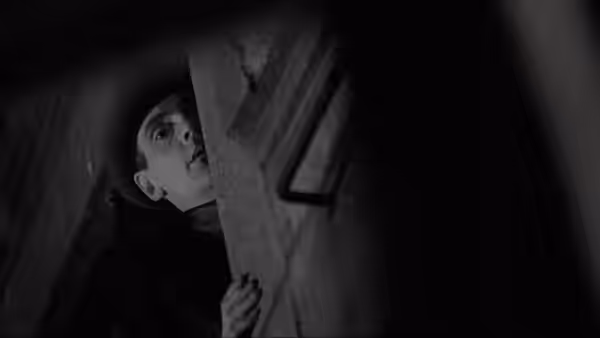 Kafka (Jeremy Irons) peering around a stone wall in darkness