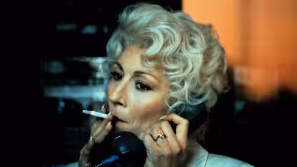 Lilly Dillon (Anjelica Huston) smoking a cigarette while talking on the phone