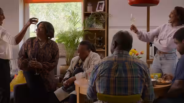 A group of friends and family gathered around a table raising glasses in a bright room