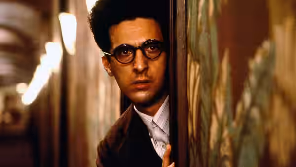 Barton Fink (John Turturro) peers cautiously from behind patterned door