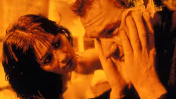 a woman touching the face of a distressed man in warm light
