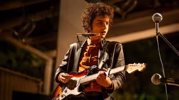 Bob Dylan (Timothée Chalamet) plays electric guitar and sings on stage
