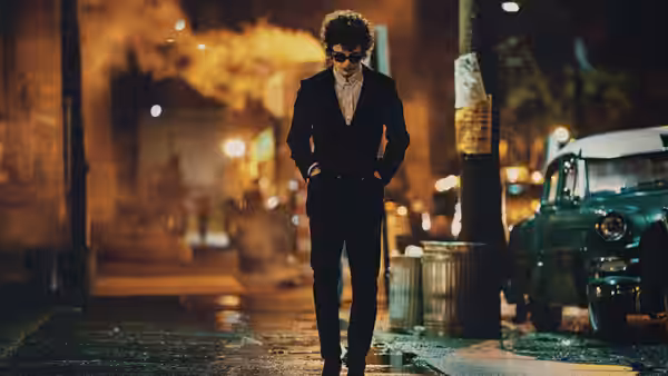 Bob Dylan (Timothée Chalamet) stands on a wet city street at night