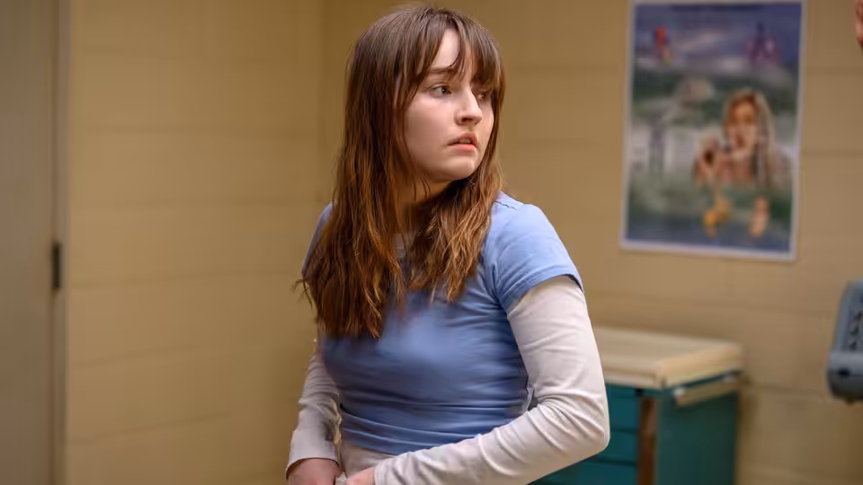 Young woman in blue shirt standing with arms crossed in clinic room