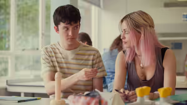 Otis (Asa Butterfield) and Maeve (Emma Mackey) examining an object at a classroom table
