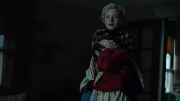 Charlotte (Julia Garner) holding Ginger in a dimly lit room