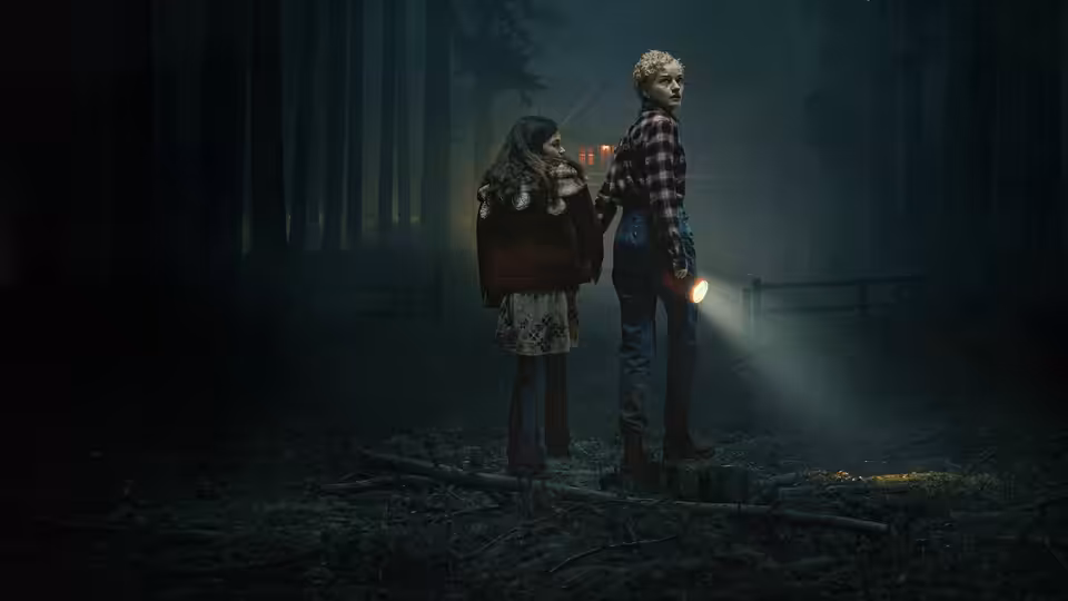 Charlotte (Julia Garner) and Ginger in a dark forest at night