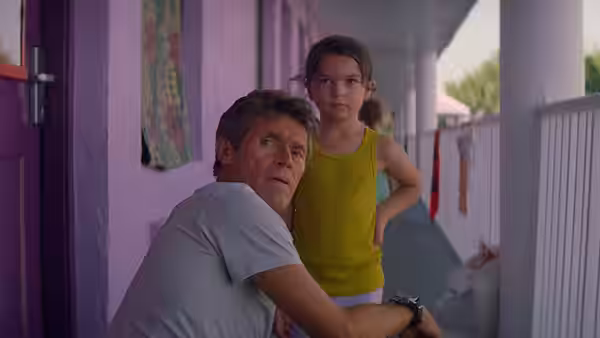 Bobby (Willem Dafoe) crouches on a motel walkway beside Moonee (Brooklynn Prince)