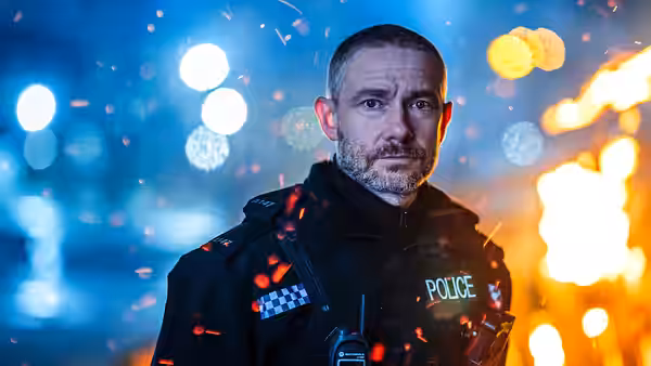 Chris Carson (Martin Freeman) standing amid sparks with blurred lights behind him
