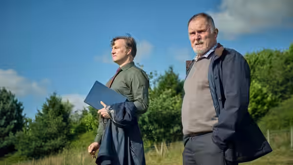 David Morrissey and another man standing in a grassy field