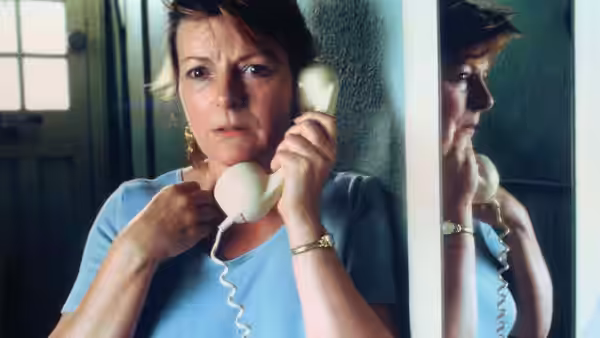 Cynthia (Brenda Blethyn) holding a telephone receiver with her reflection visible
