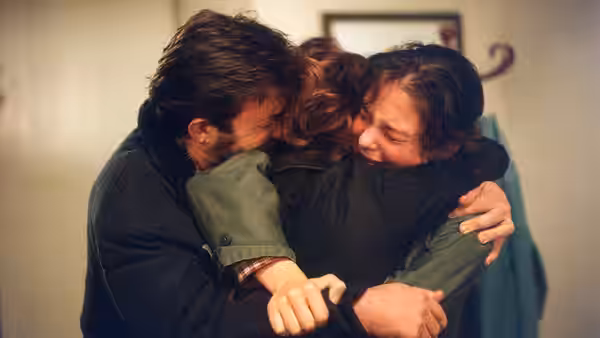 Giovanni embraces two family members inside their home