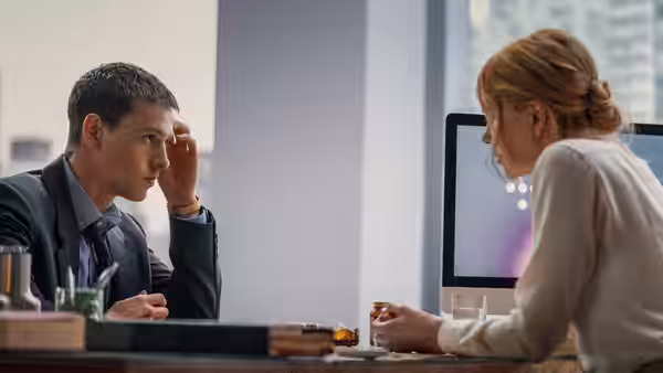 Samuel (Harris Dickinson) and Romy (Nicole Kidman) talking at an office desk