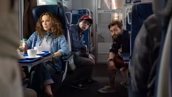 Woman and two men seated together inside a train carriage