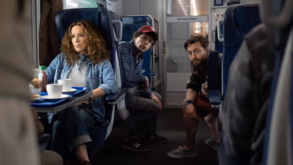Woman and two men seated together inside a train carriage
