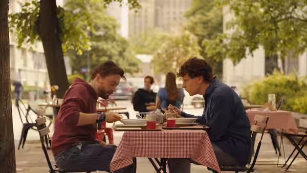 Benji Kaplan (Kieran Culkin) and David Kaplan (Jesse Eisenberg) at an outdoor cafe table