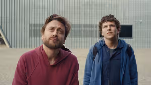 Benji Kaplan (Kieran Culkin) and David Kaplan (Jesse Eisenberg) standing in a courtyard