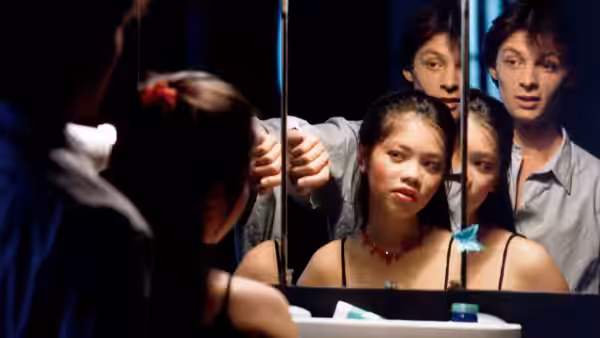 Young woman and two men peer through a large window