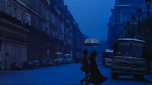 Couple walks under an umbrella on a city street at night